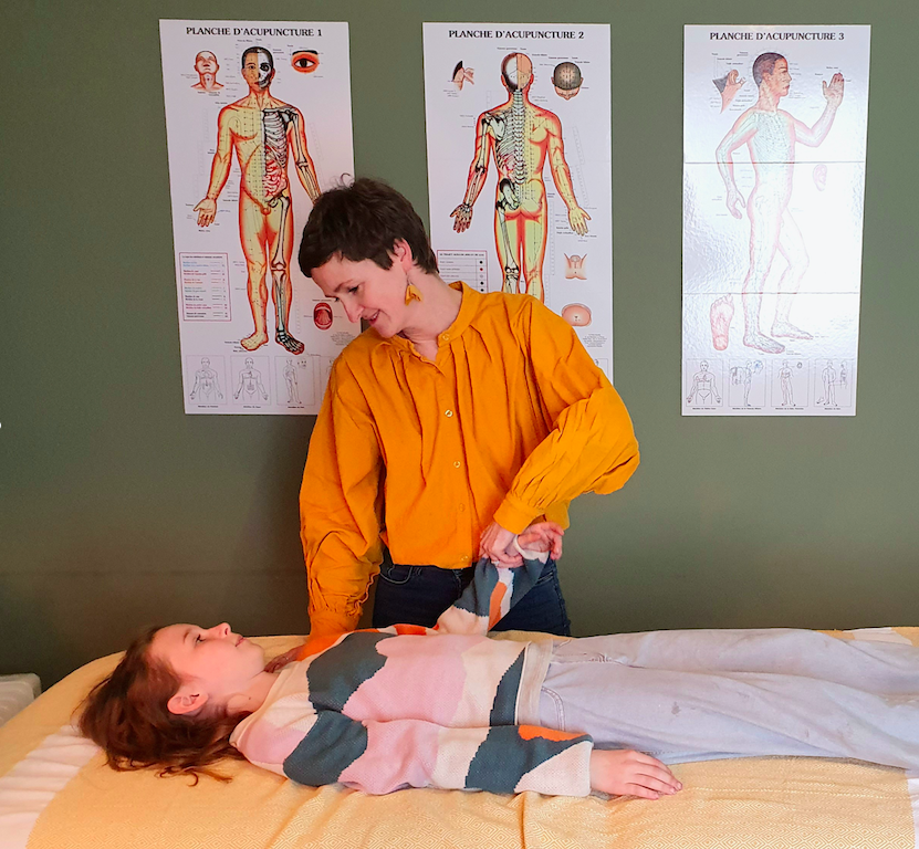 KINESIOLOGUE EFFECTUANT LE TEST MUSCULAIRE sur un enfant couché sur la table
